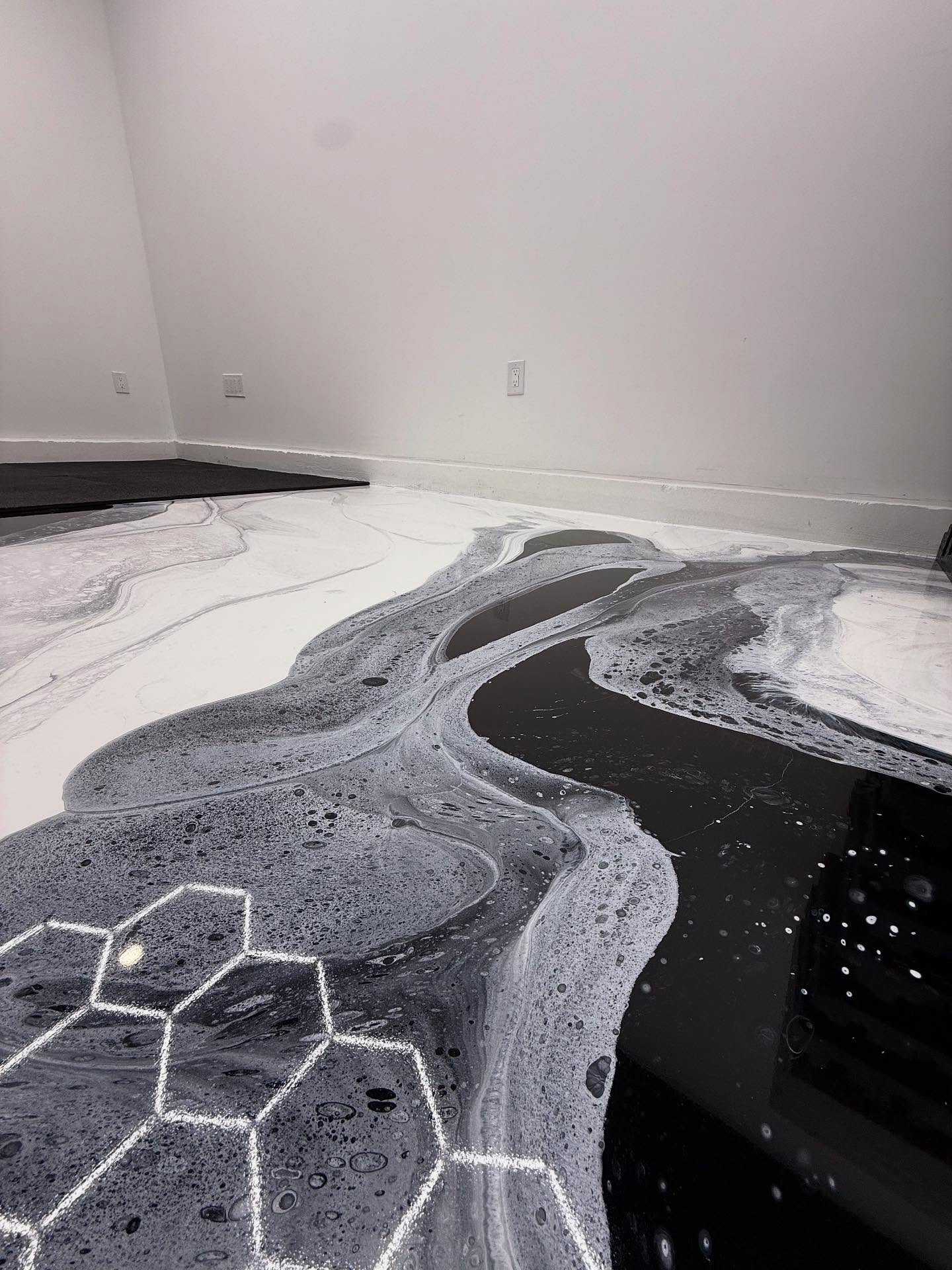 Black silver and white metallic epoxy floor mid-pour in a Los Angeles commercial garage, reflecting hexagonal LED ceiling lighting