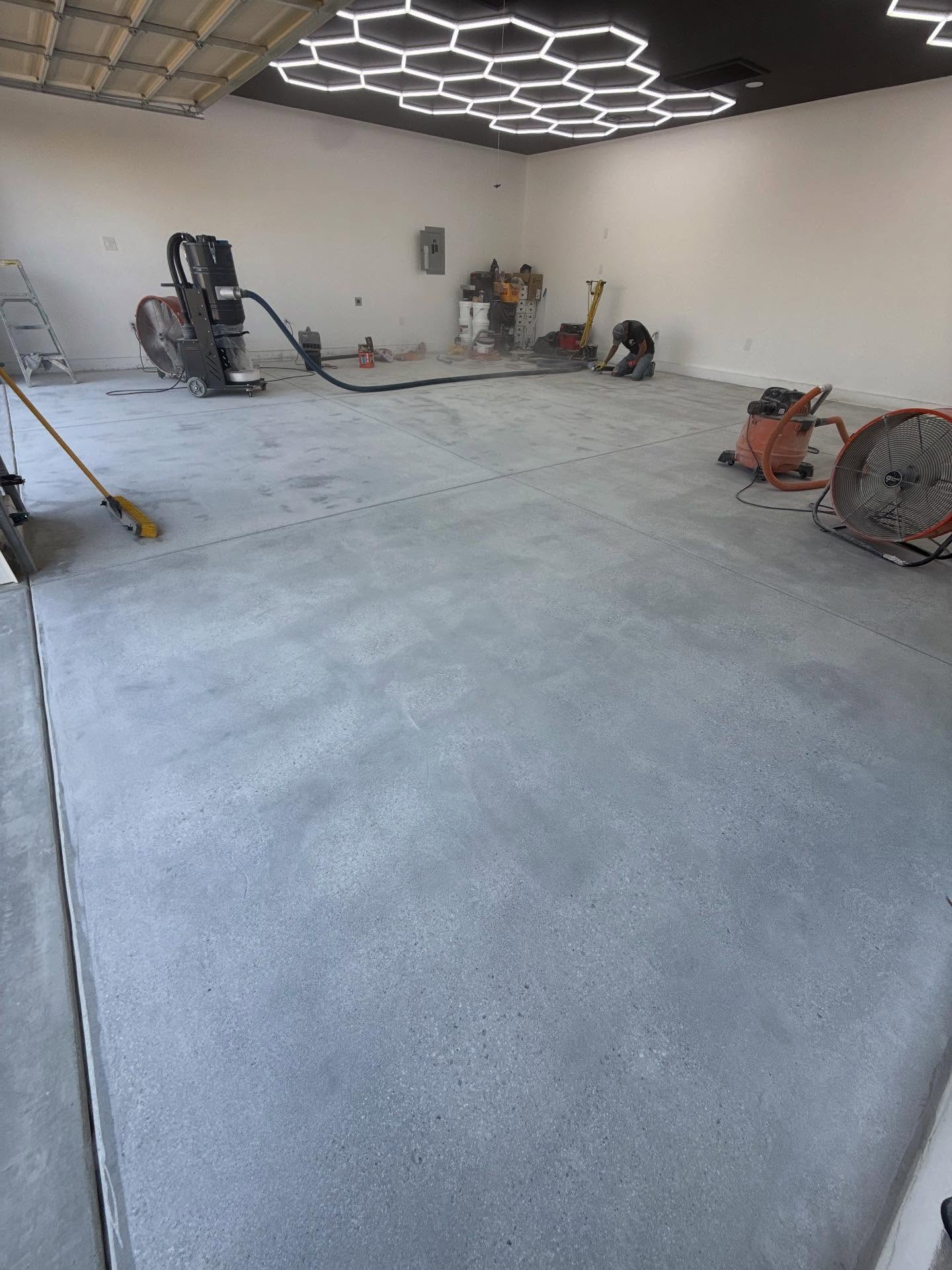 Concrete surface prep with grinder and dust extraction in a Los Angeles commercial garage, hexagonal LED ceiling visible