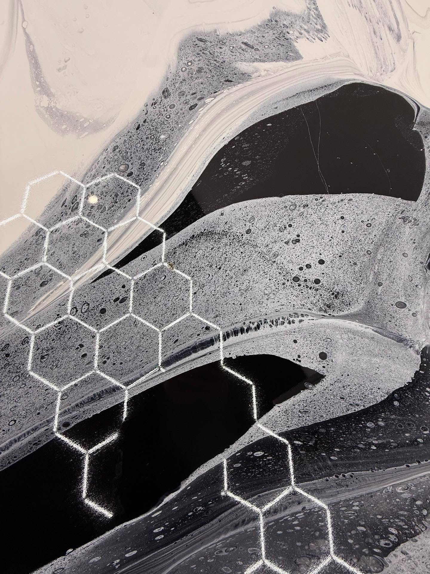 Close-up of black and silver metallic epoxy floor with hexagonal LED reflection over swirled pigment, Los Angeles